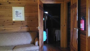 Un intérieur en bois avec un canapé, un ventilateur de plafond, un tableau encadré et un extincteur.