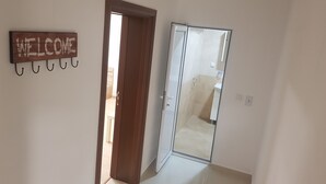 Ein Flur mit einer Holztür, einer Glastür und einem Schild mit der Aufschrift 'WELCOME' an der Wand.