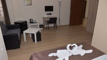 Habitación de hotel con cama, escritorio, silla, televisión y perchero.