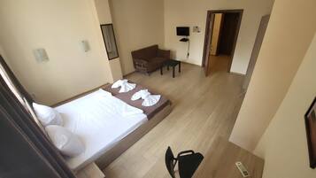 A hotel room with a bed, a desk, a chair, and a TV.
