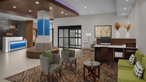 A modern lobby with a reception desk, seating area, and a flat-screen TV.