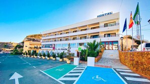 A multi-story hotel with a sign reading "HOSTAL" and a wheelchair-accessible parking area. - Hostal Sorbas (Sorbas)