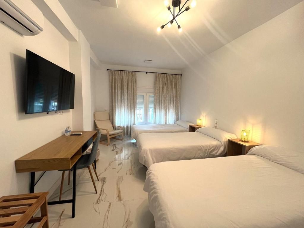 Une chambre d’hôtel équipée d’un téléviseur à écran plat, d’un bureau en bois, de deux lits, d’une chaise et d’une fenêtre avec des rideaux.