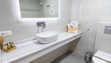 Un baño moderno con un espejo grande, un lavamanos blanco y un inodoro.