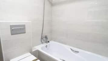 Un baño con inodoro blanco, bañera y ducha.