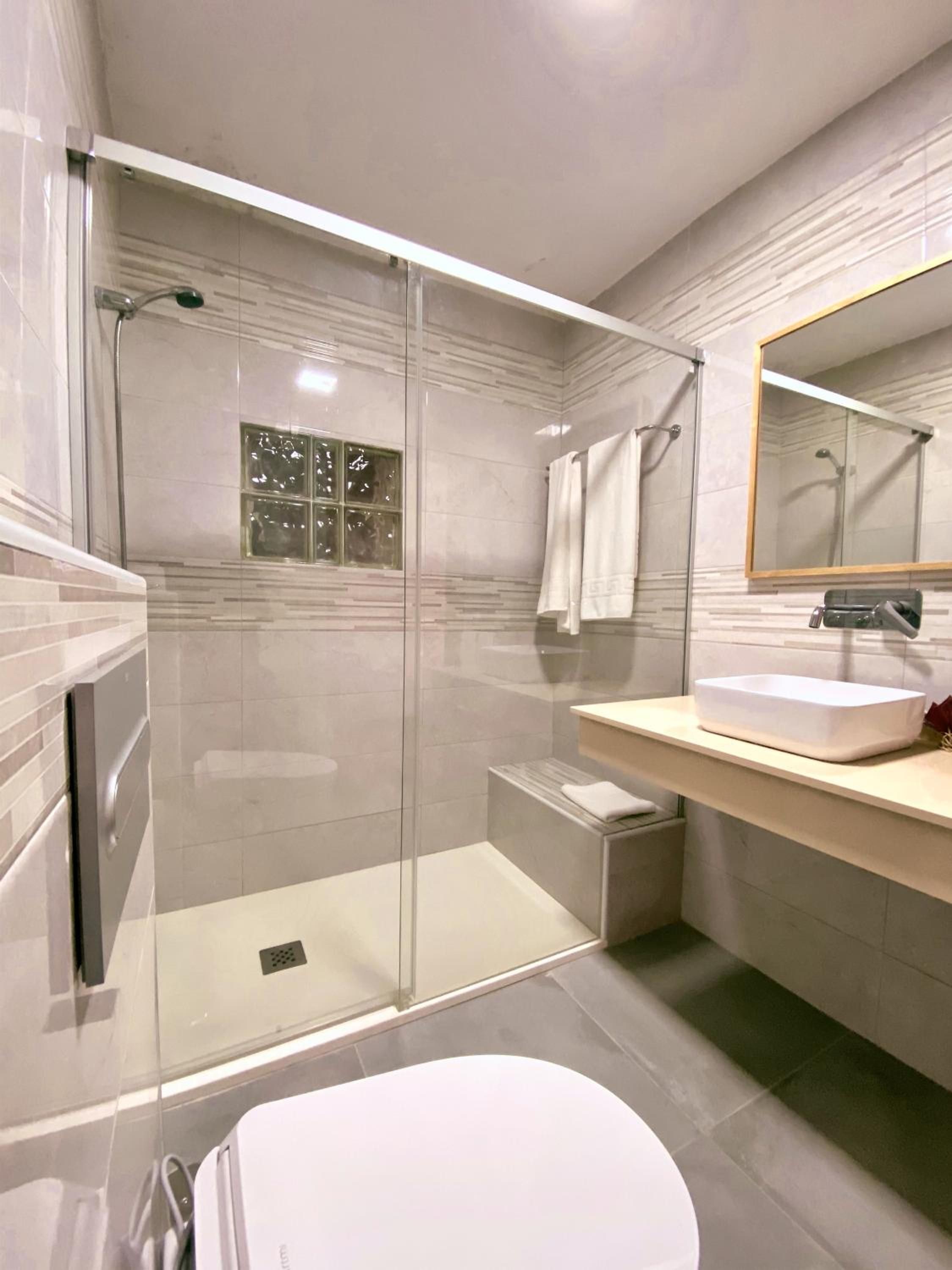 Une salle de bain moderne avec une douche à parois de verre, un lavabo blanc et un grand miroir.