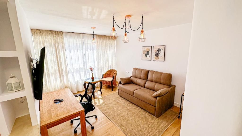 A furnished living room with a sofa, a coffee table, a TV, and a chandelier.