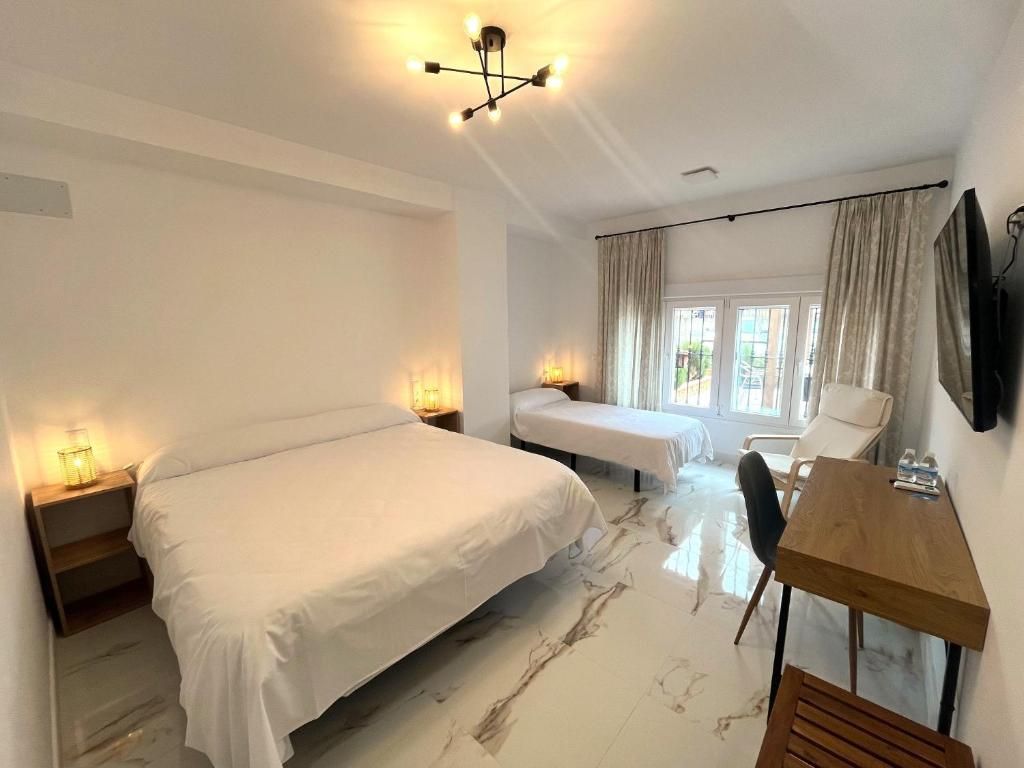 Ein Hotelzimmer mit einem großen Bett, einem kleineren Bett, einem Schreibtisch und einem Sessel.