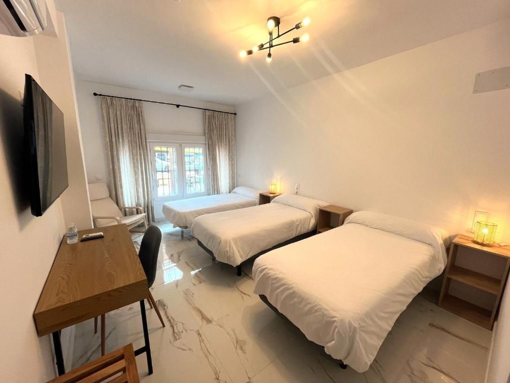 A hotel room with two beds, a desk, a chair, a TV, and a window with curtains.