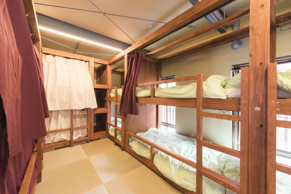 A bunk bed room with tatami flooring and wooden beams.