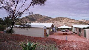A rural setting with a building that has a sloped roof and a covered outdoor seating area.
