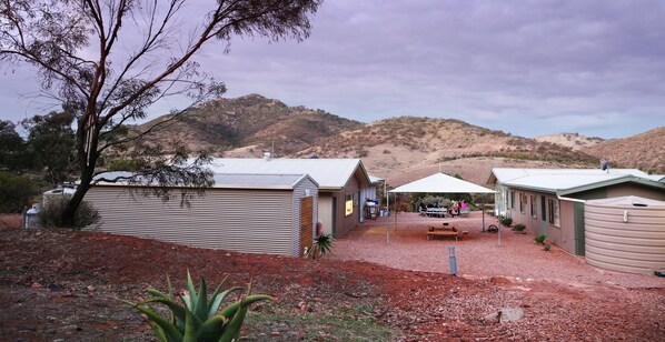 A rural setting with a building that has a sloped roof and a covered outdoor seating area. - Pichi Richi Park (Quorn)