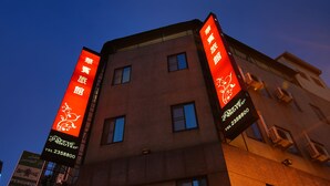 Un hotel con dos grandes pancartas verticales que muestran el nombre y los datos de contacto.