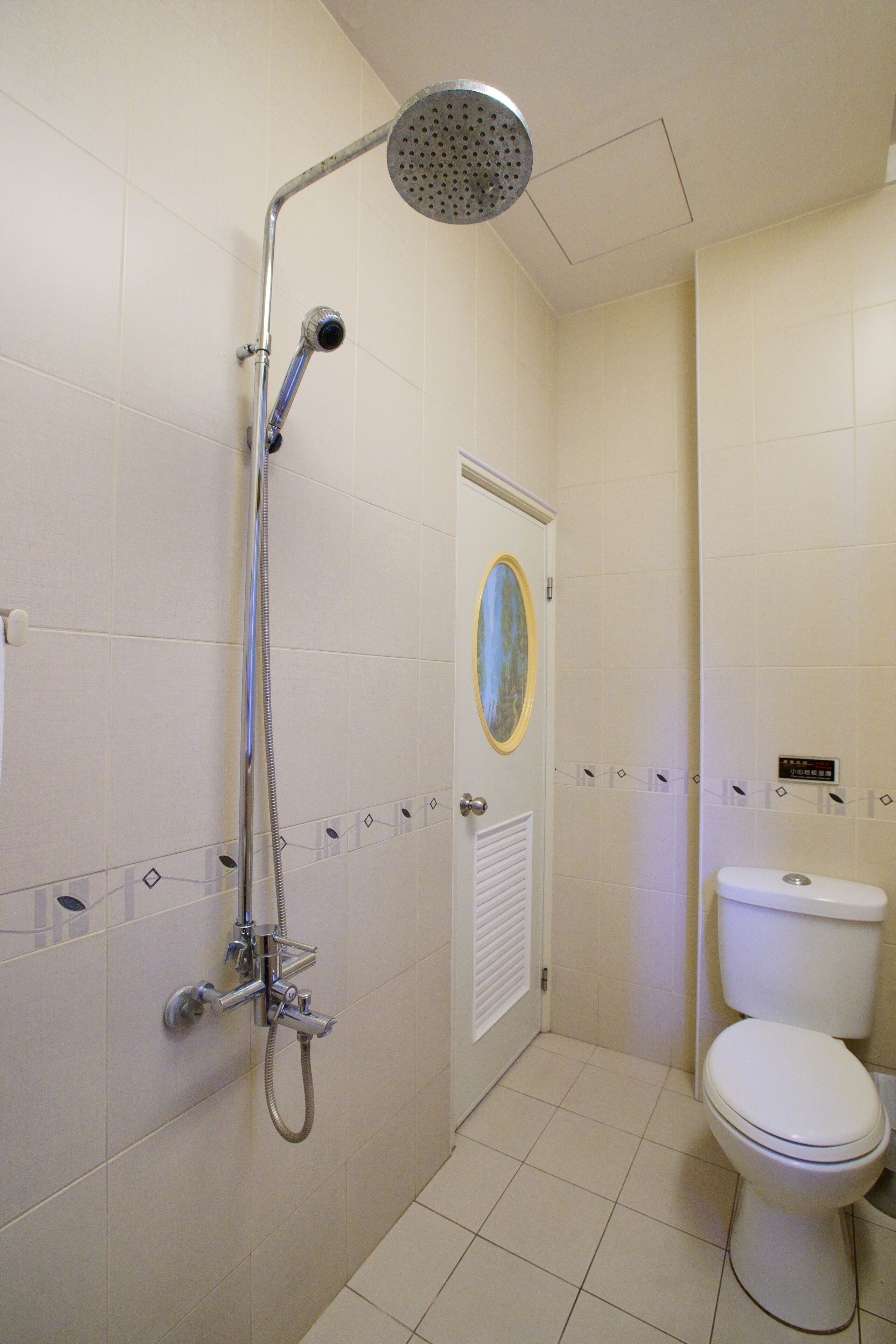 Une salle de bain avec une douche, des toilettes et une porte dotée d’un miroir.