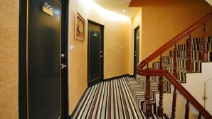 Un pasillo con puertas negras, alfombra a rayas y una escalera de madera.