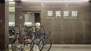 Entrada de un hotel con un letrero que dice 'HAPPY HOTEL' y varias bicicletas estacionadas afuera.