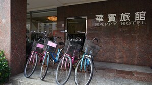 Entrada de un hotel con un cartel que dice 'Happy Hotel' y bicicletas estacionadas afuera.