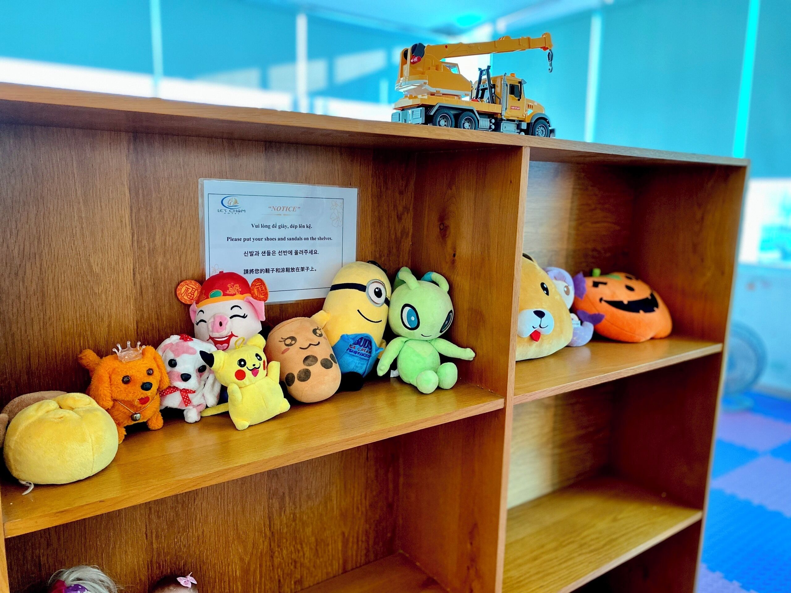 A wooden shelf with plush toys and a toy crane.