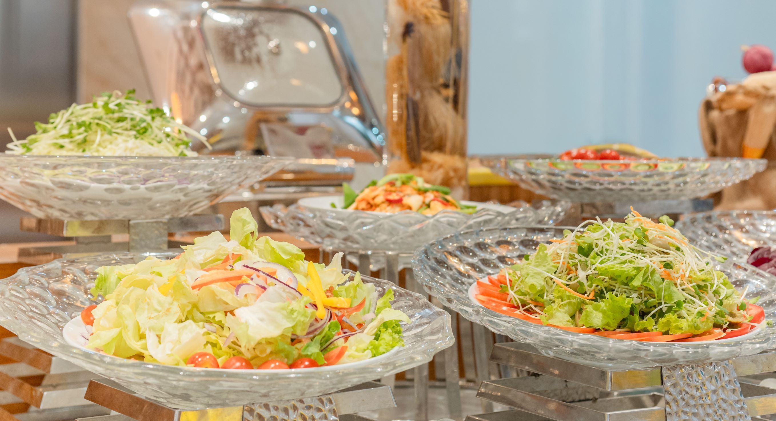 Un buffet proposant diverses salades, présentées dans des plats en verre.