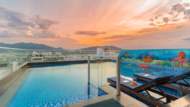 Piscina infinita en la azotea con vistas a la ciudad y montañas, un mural de una escena submarina y sillones de descanso.