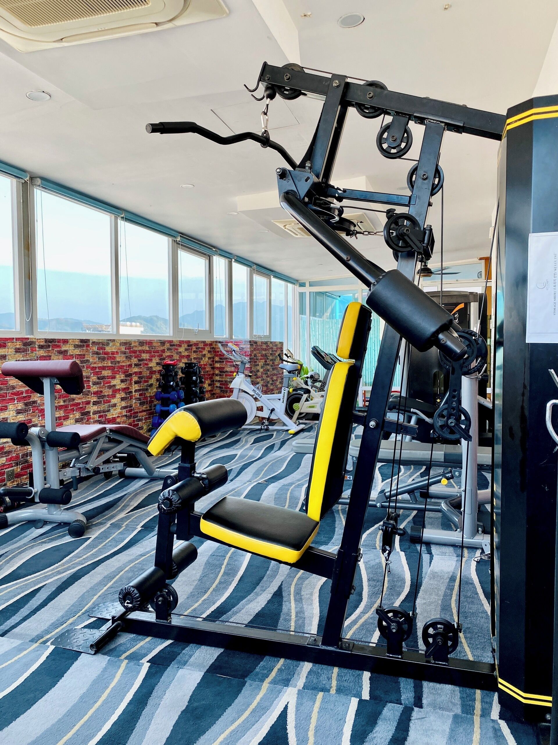 Un gimnasio con equipo de ejercicio, una banca y ventanas amplias que ofrecen vistas.