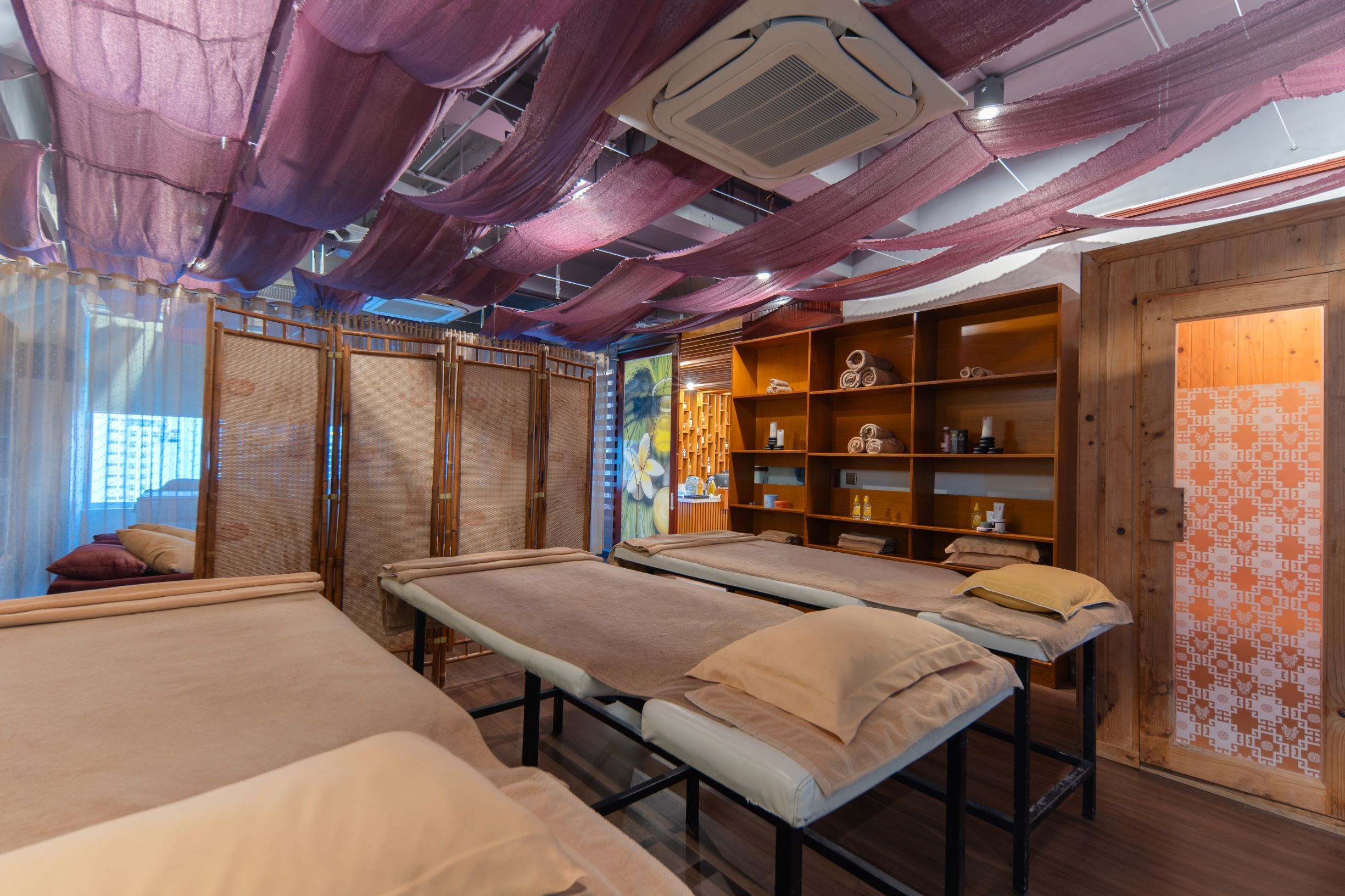 Una habitación con varias camas, estanterías de madera con diversos objetos y una pared con diseño.