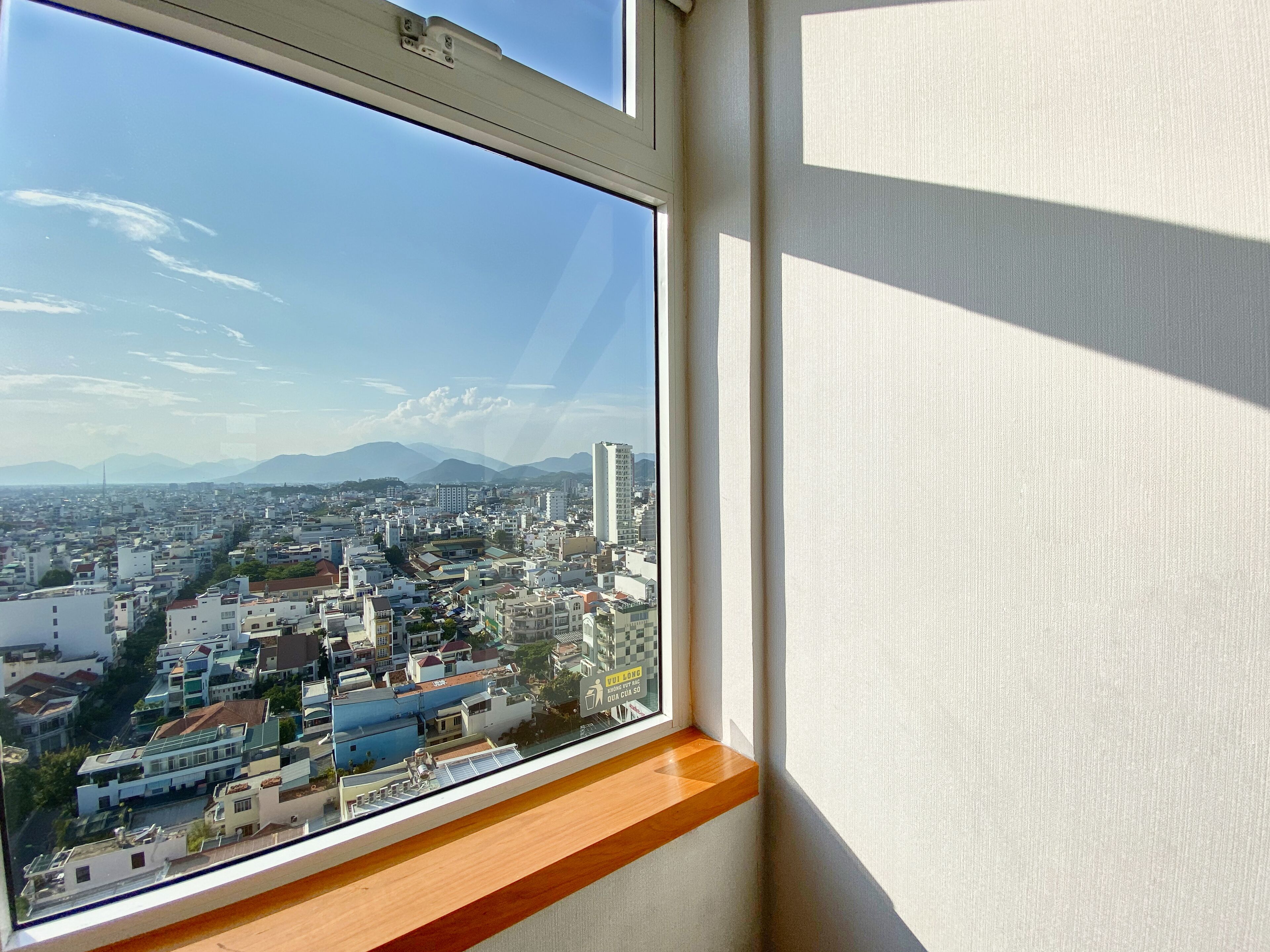 Una ventana con vista a un paisaje urbano, que incluye edificios y montañas.