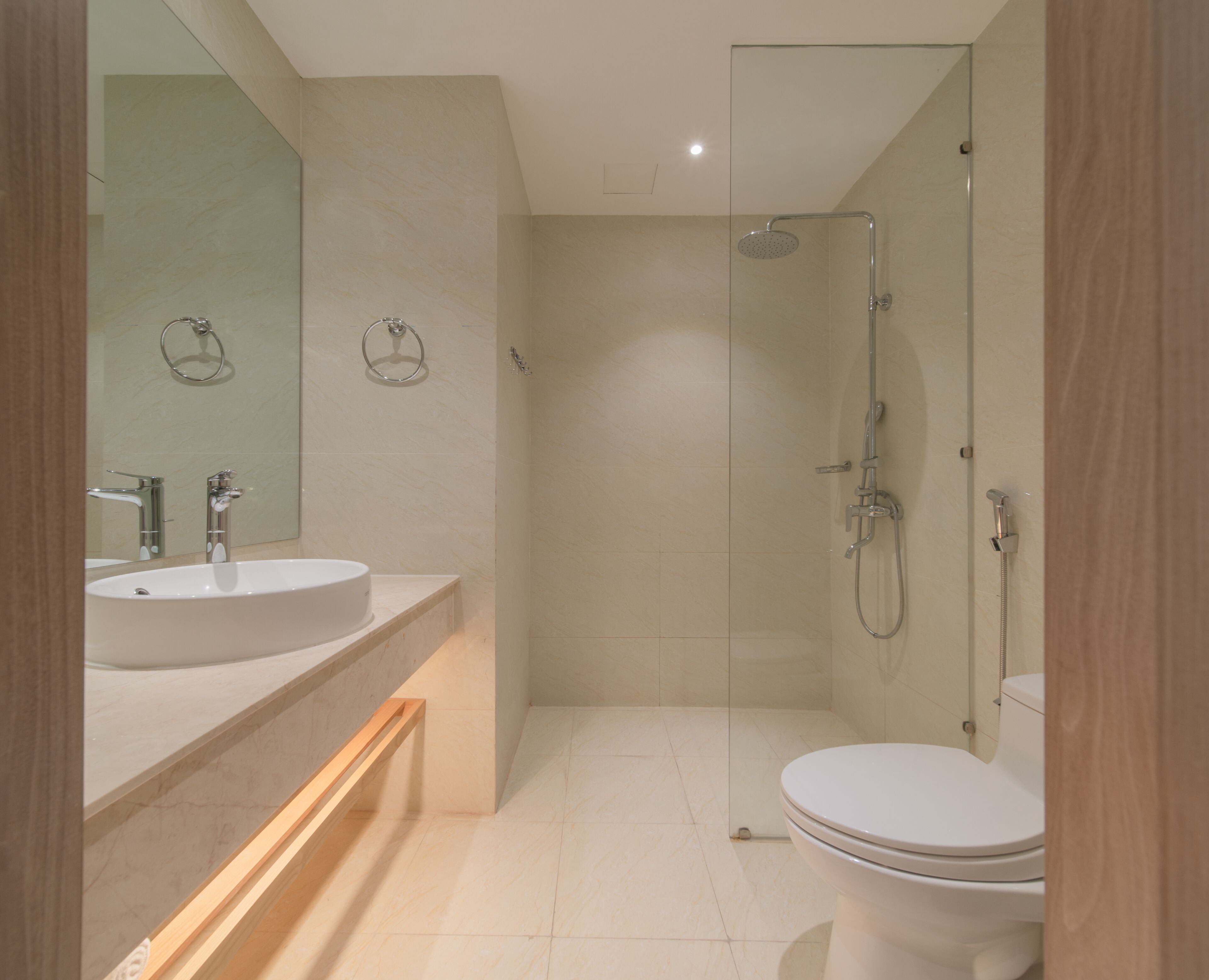 Un baño moderno con ducha de vidrio, lavamanos con espejo y retrete.