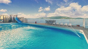 Een seizoensgebonden buitenzwembad, ligstoelen bij het zwembad