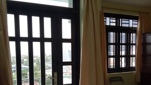 A room with a sliding glass door leading to an outdoor area, a bed with a colorful bedspread, and a chair near the window.