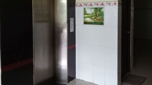 A hallway with an elevator, a wall-mounted sign, and a tiled floor.