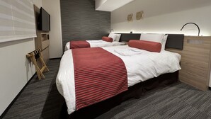 Habitación de hotel moderna con dos camas, un televisor de pantalla plana, una mesita de noche de madera y una lámpara fijada a la pared.