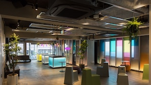 A modern office space with a wooden floor, seating areas, and potted plants. - UNPLAN Shinjuku – Hostel (Tokyo)