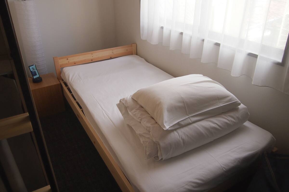 A single bed with white bedding in a room with a wooden headboard.