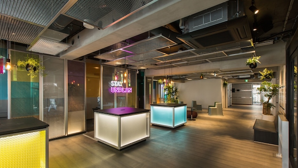 An office space with modern design, featuring a neon sign, illuminated cubicles, and hanging plants. - UNPLAN Shinjuku – Hostel (Tokyo)