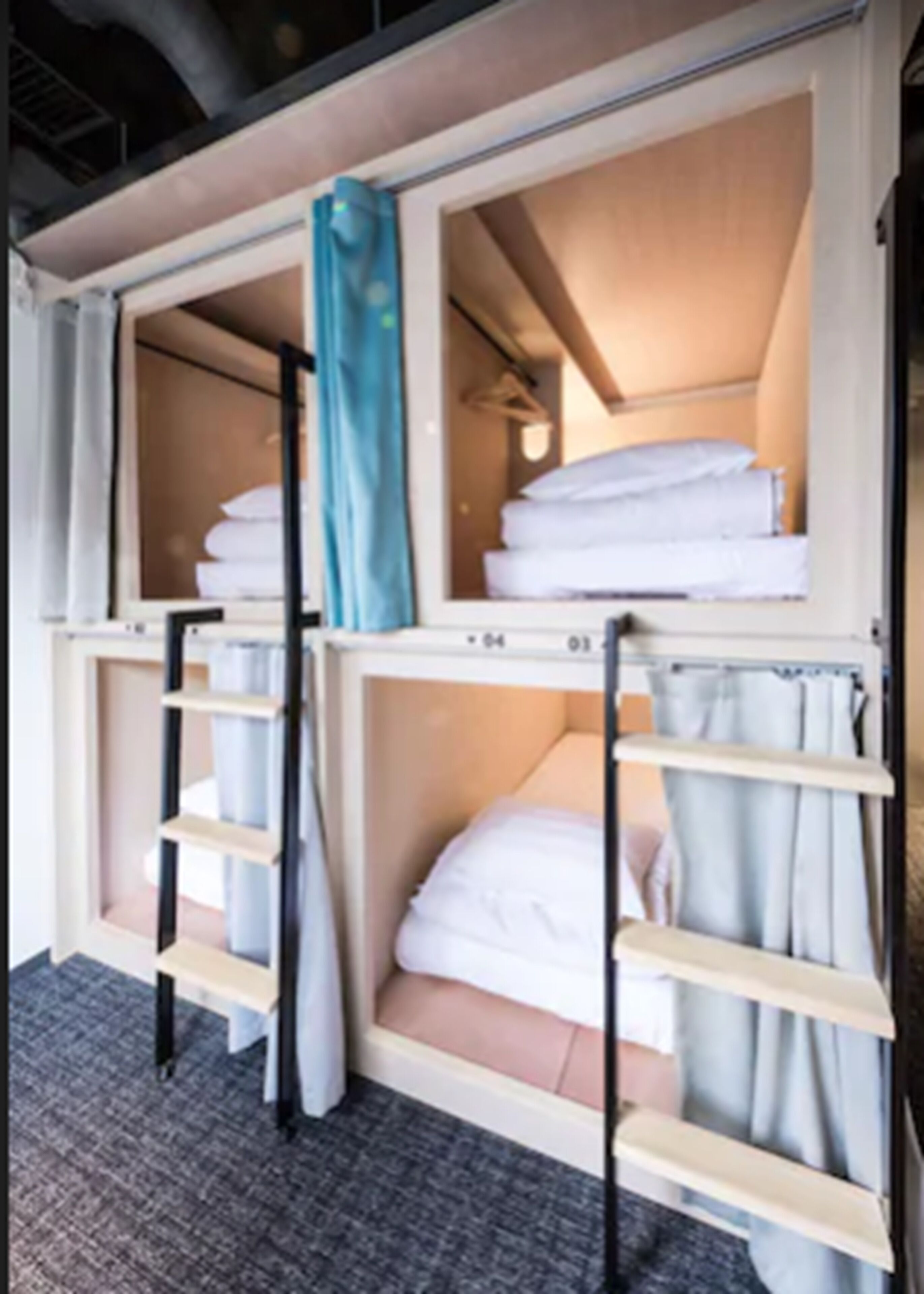 Habitación de hotel con literas, una escalera y un ventanal con cortinas.