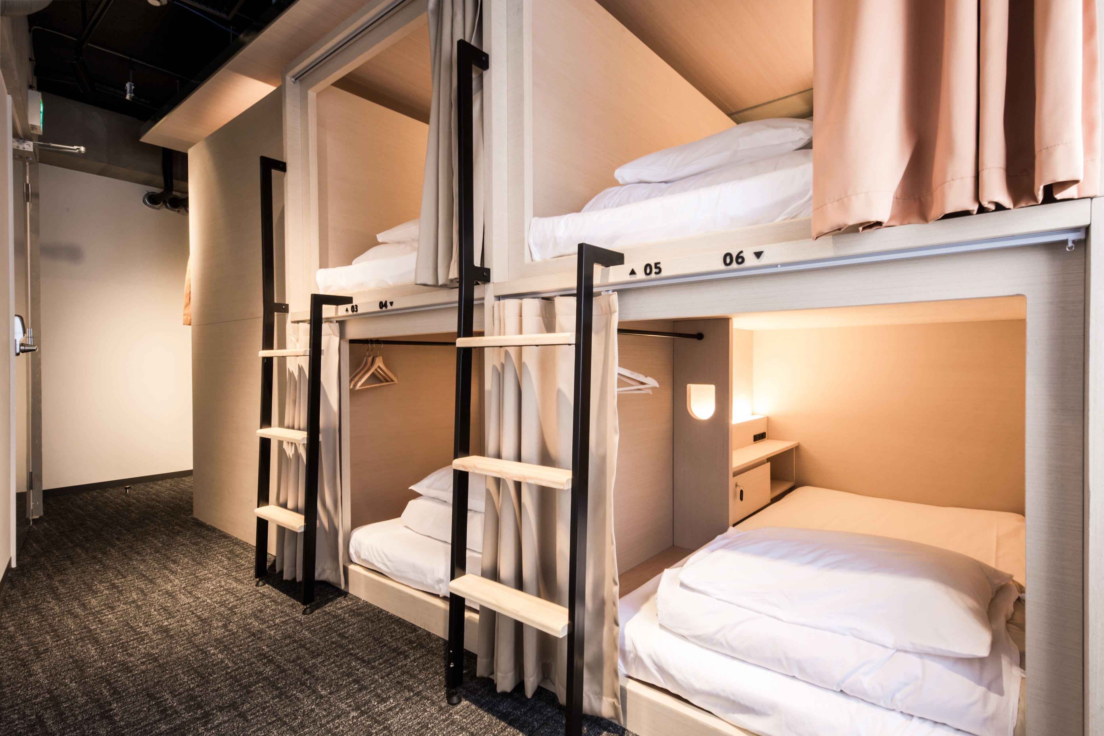A hotel room with bunk beds, a wardrobe, and a bedside table.