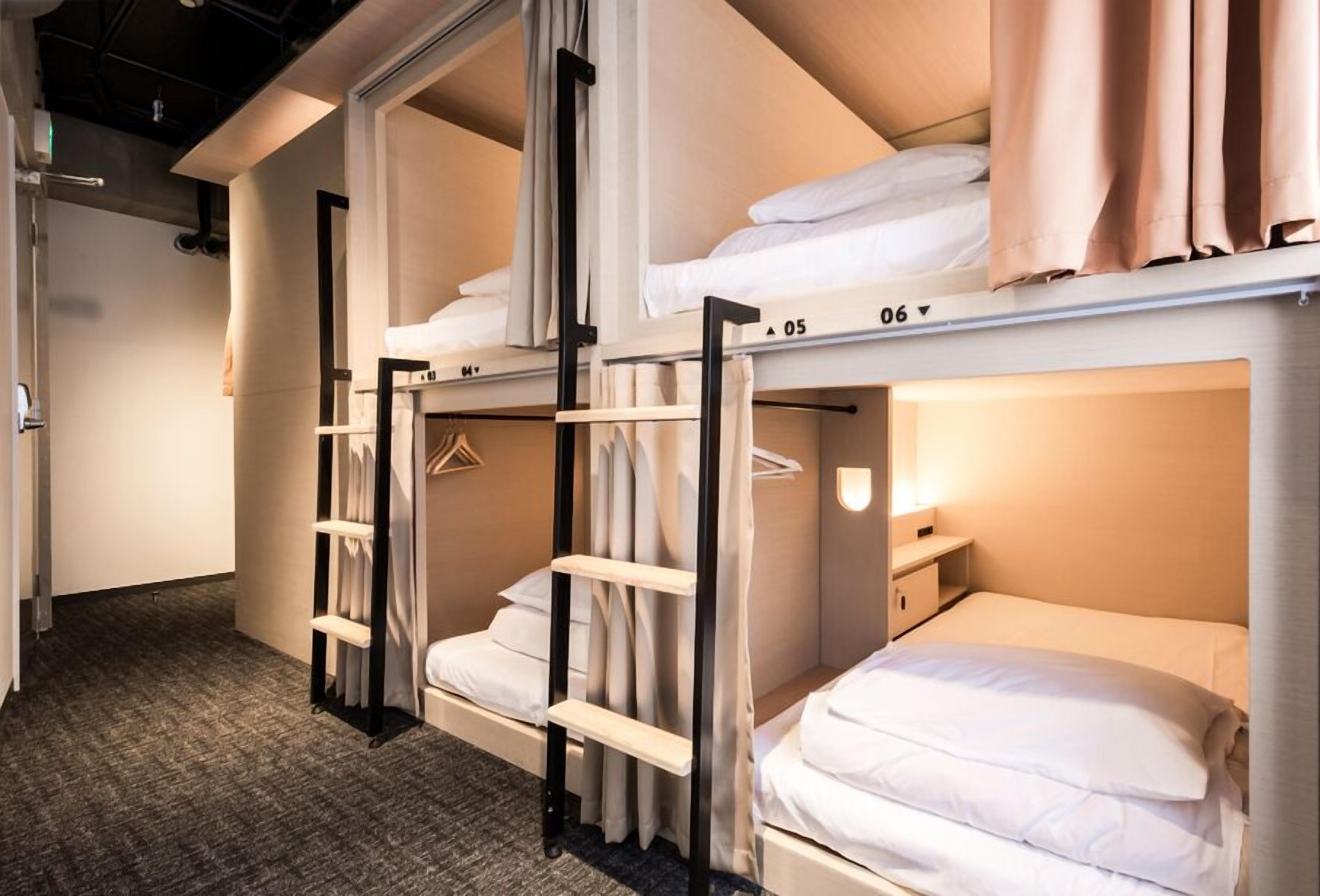 A hotel room with bunk beds, a wardrobe, and a bedside table.