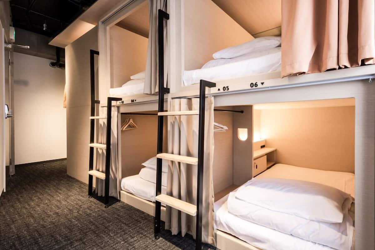 A hotel room with bunk beds, a wardrobe, and a bedside table.