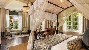 A bedroom with a four-poster bed, a canopy, striped chairs, and a chandelier. - Castle Hill Bungalow by Seven Angels (Kandy)