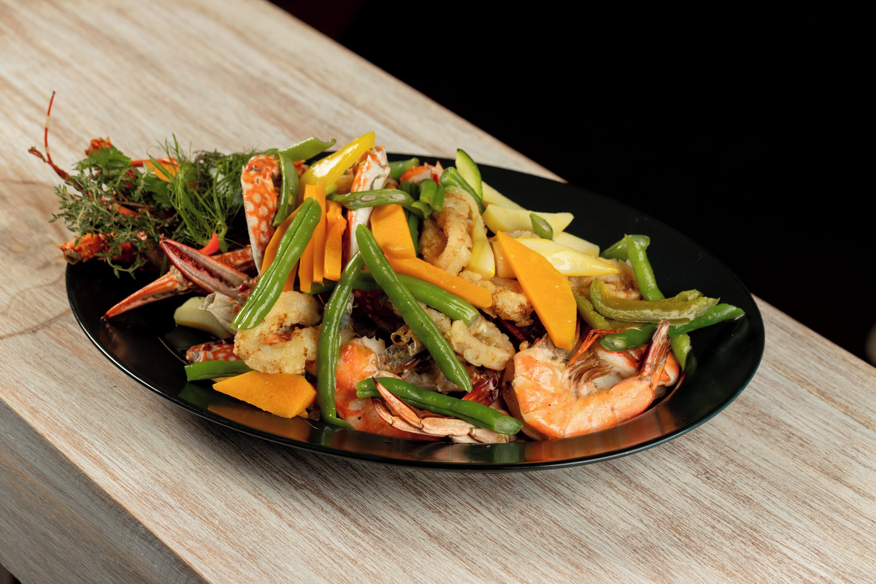 Un plato de mariscos y verduras sobre una mesa de madera.