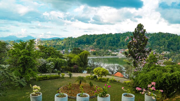 A view of a lush garden with potted plants and a scenic landscape in the background. - Castle Hill Bungalow by Seven Angels (Kandy)