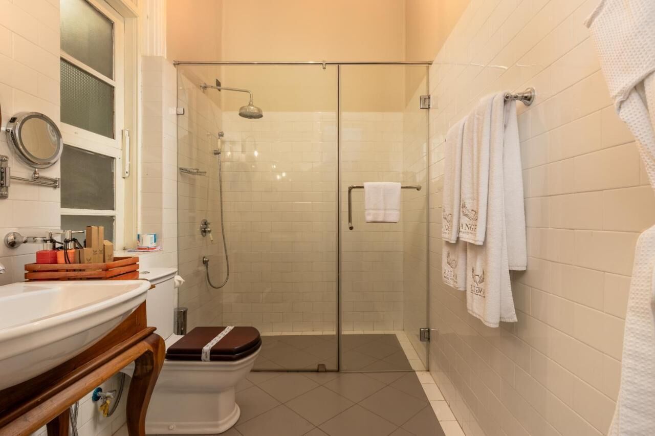 A bathroom with a glass-enclosed shower, a toilet, a sink, and a mirror.