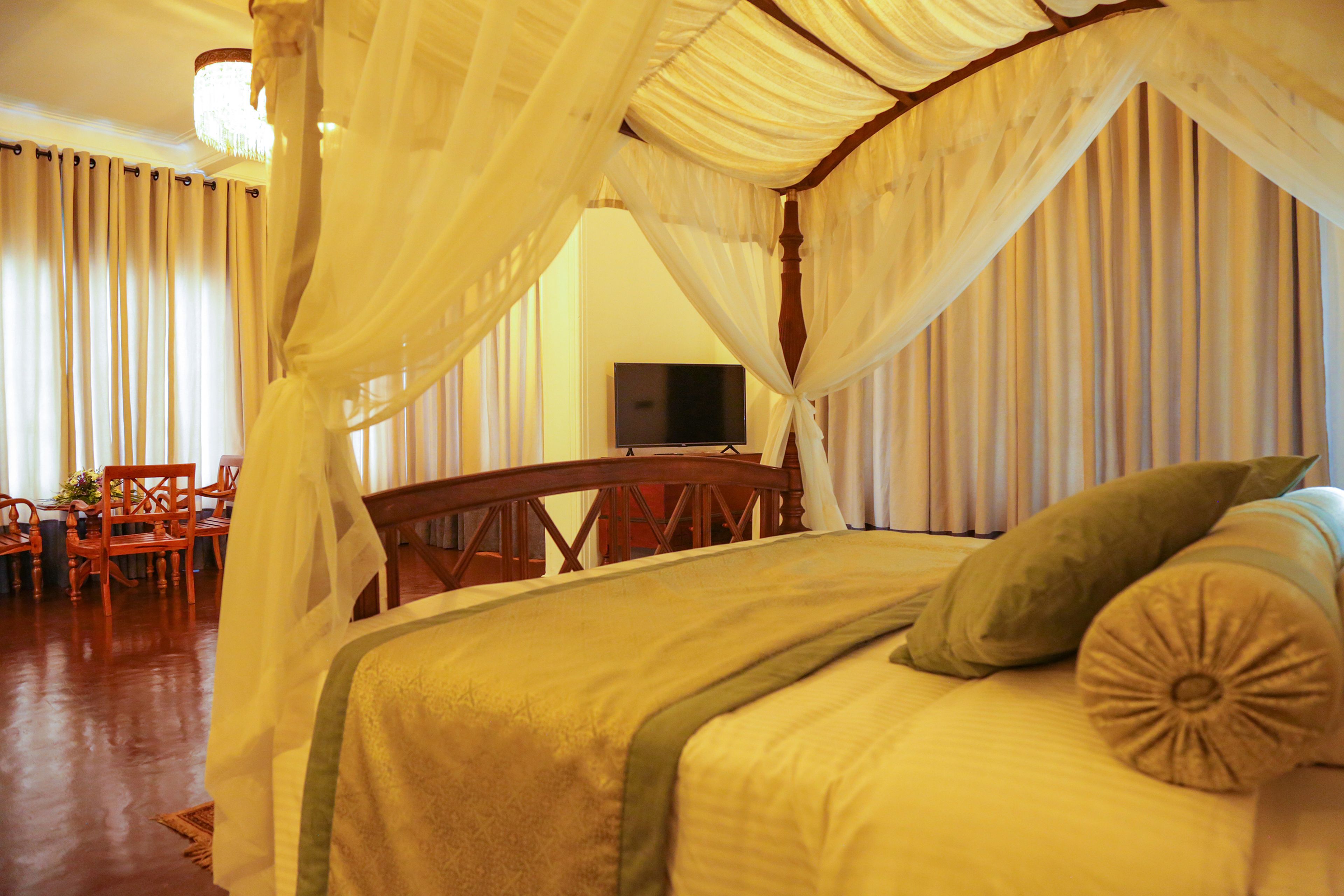Una habitación con cama, televisión y comedor con sillas y mesa.