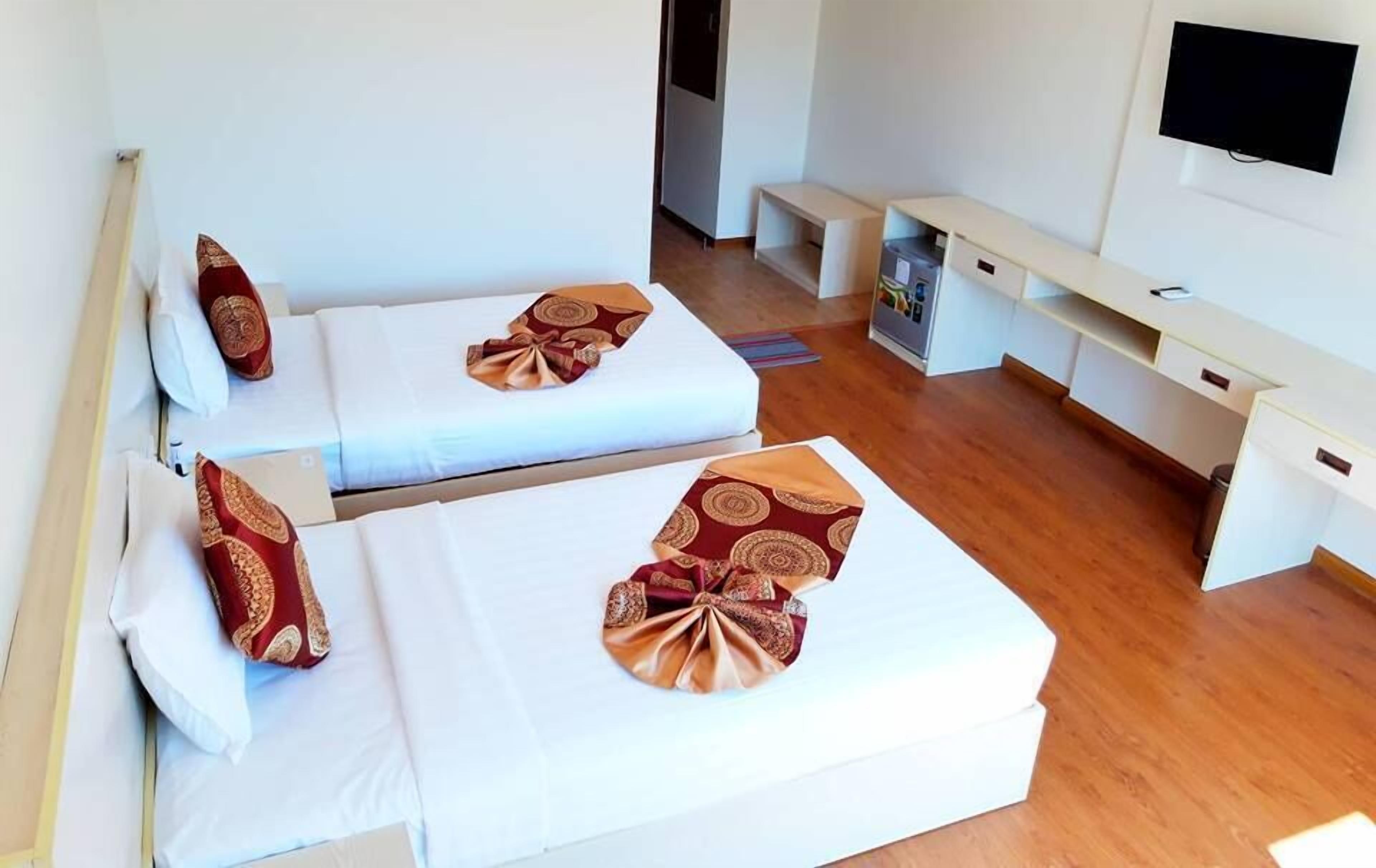 Una habitación de hotel con dos camas, un televisor y un banco.