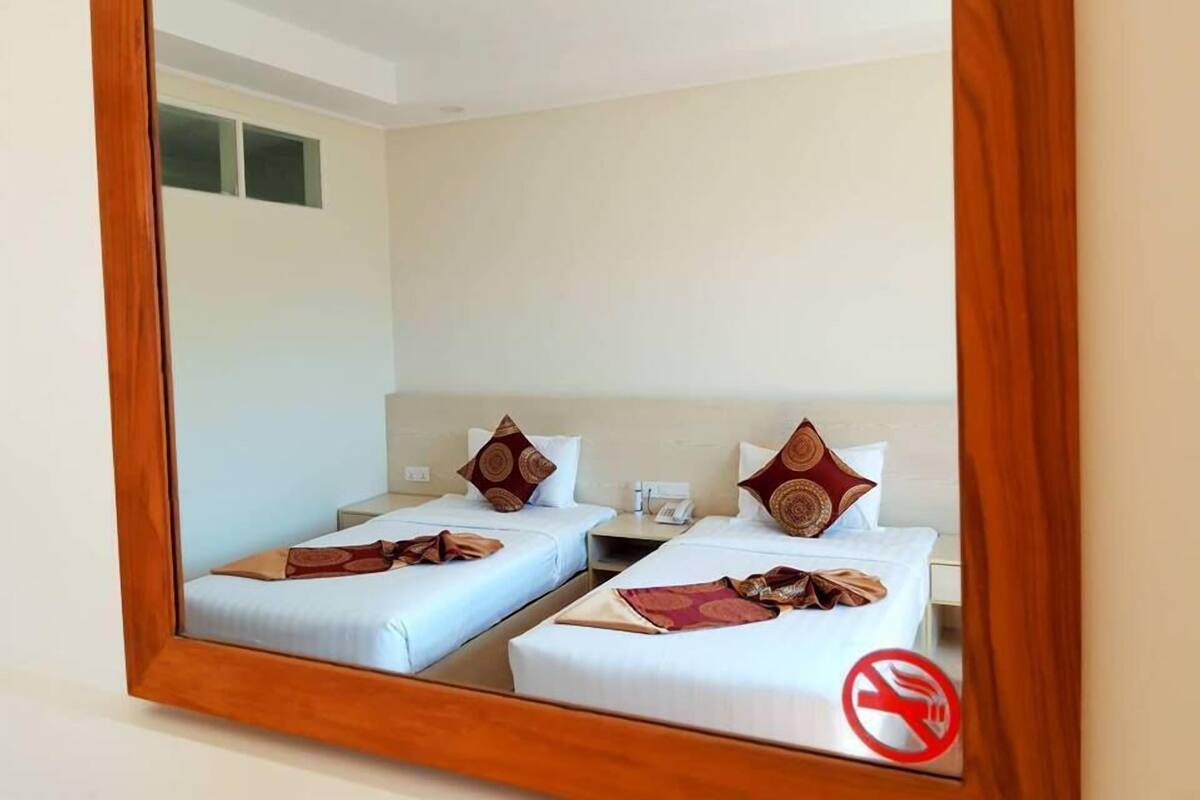 A hotel room with two beds, each with a pillow and a blanket.