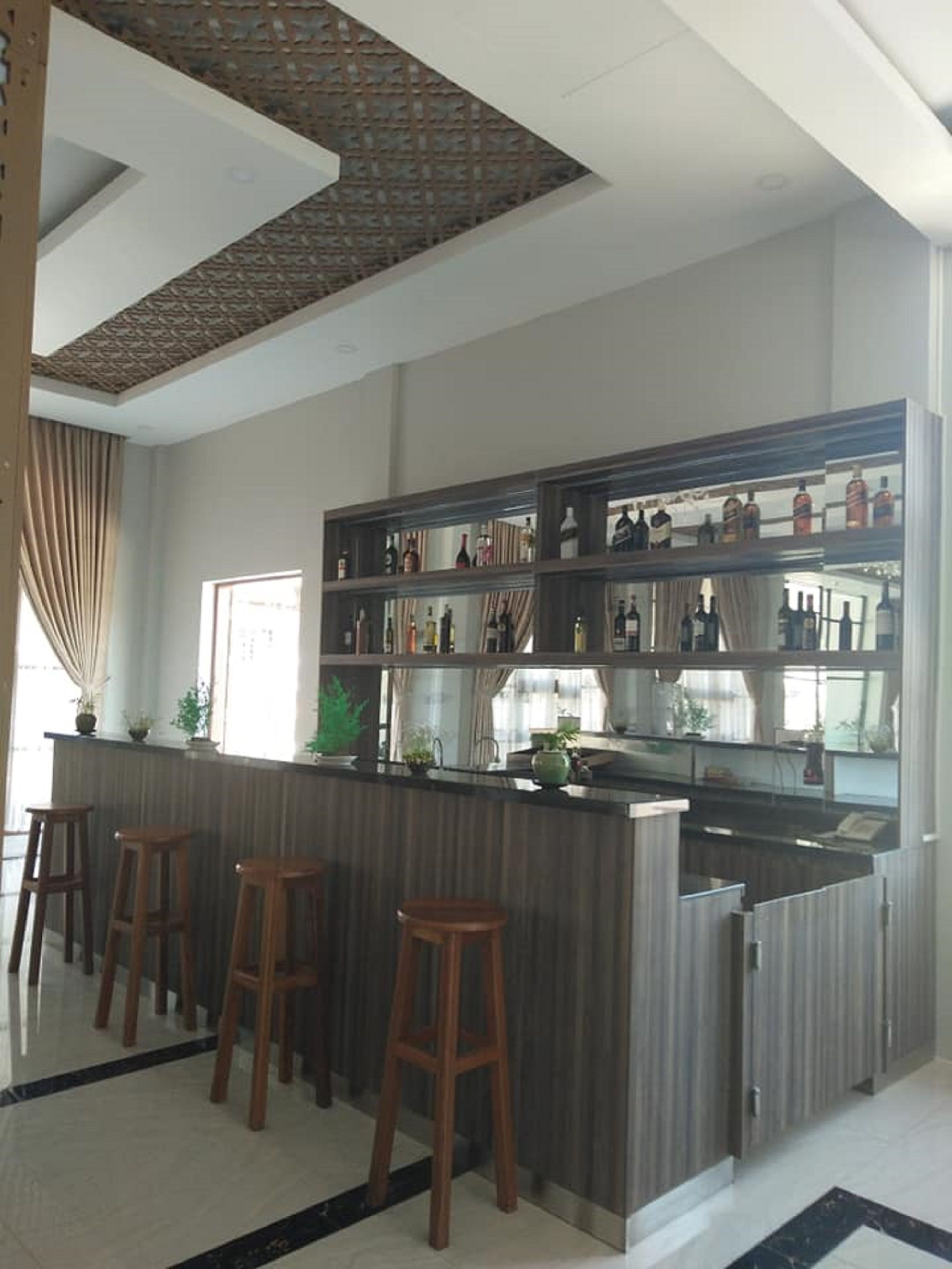A modern kitchen with a central island, bar stools, and a variety of bottles on shelves.