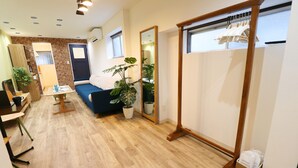 Una habitación moderna con suelo de madera, un sofá azul, un espejo grande y un perchero.