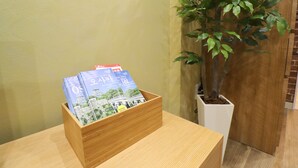 Una caja de madera con revistas sobre una mesa junto a una planta en maceta.