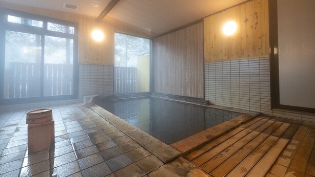 A traditional Japanese onsen with a wooden deck and tiled walls. - Tabist Kazeyuki (Takayama)